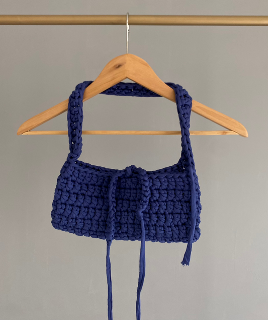 Sac baguette en crochet bleu sur un cintre